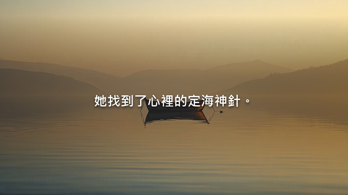 晨光薄霧裡，平靜如鏡的水面上停著一艘小木船，遠處是連綿的山。