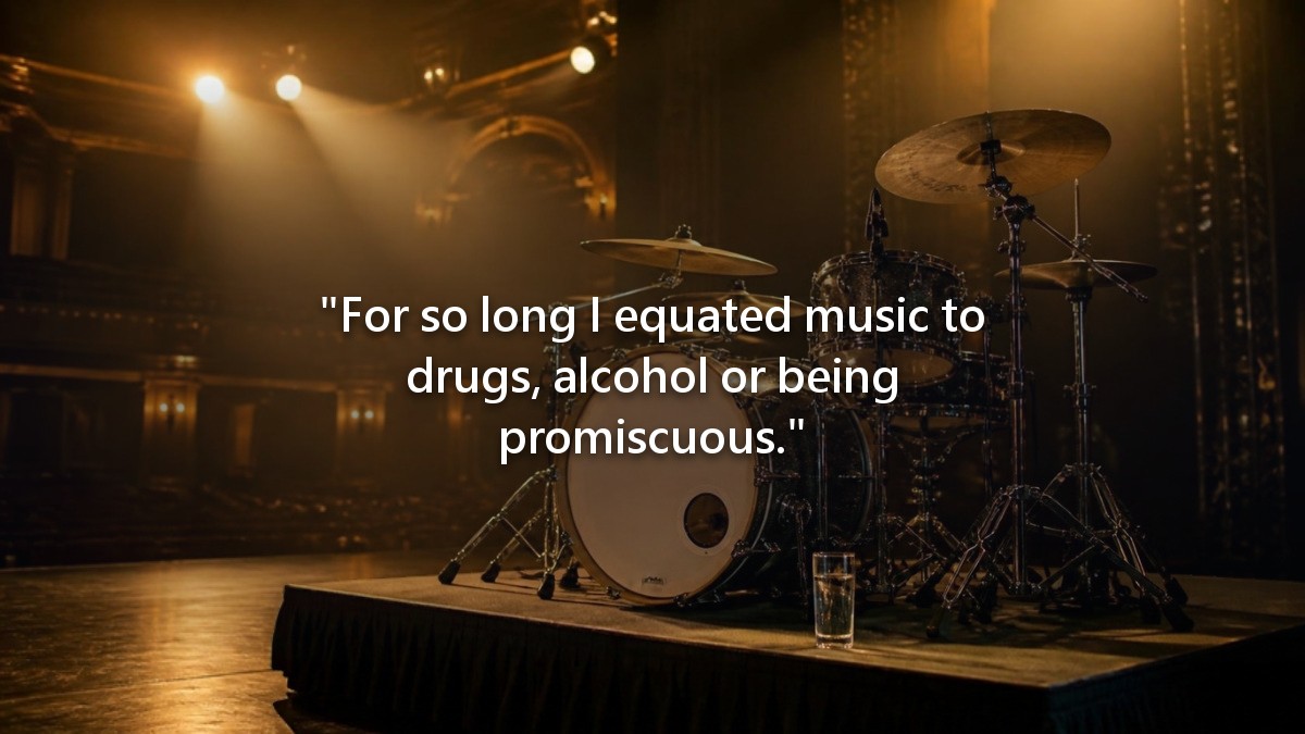 A drum kit on an empty stage before a show, a glass of water on the riser beside it.